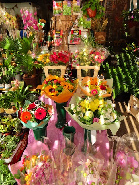 A vibrant display of floral arrangements in a flower shop, showcasing fresh bouquets of brightly colored flowers such as red, yellow, pink, and white blooms, wrapped in decorative paper and arranged i