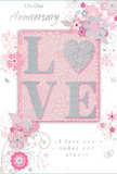 This elegant anniversary card, perfect to accompany flowers delivered across Harrow on the Hill, blends romantic design with a serene, modern softness. The central feature is the word LOVE, rendered in large, raised letters that shimmer with a dusting of pale glitter. Each letter appears lightly embossed, with the sparkle concentrated along the edges so it seems to glow softly, much like sunlight caught on the rim of a glass vase in a Harrow window. Surrounding this central word is a graceful pattern of stylised blossoms and foliage. The flowers, sketched in fine lines with subtle shading, float across a background of muted blush pink, their petals opening in shades of blush, ivory, and gentle silver-grey. The overall layout feels like the early stages of a florist's drawing, where each bloom and curve of greenery has been thoughtfully placed before being recreated in fresh stems and leaves. Silver accents trace some of the petals and vines, adding a refined sparkle reminiscent of evening walks past the lit shopfronts on the Hill. Small, whimsical details-soft curls of leaves, tiny petals, and almost-hidden butterflies-lend movement and intimacy, as if capturing fleeting moments from years of shared life. The accompanying text, written in an elegant script, offers heartfelt anniversary blessings without overwhelming the floral motif. The card radiates a sense of tender celebration and enduring affection, the paper counterpart to a romantic bouquet thoughtfully chosen to mark another year together in Harrow on the Hill.